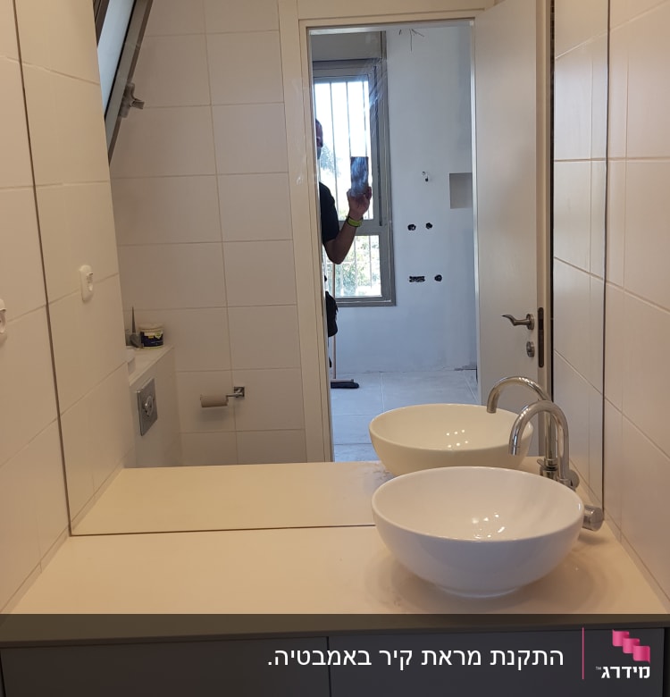 מראה גדולה על קיר חדר אמבטיה